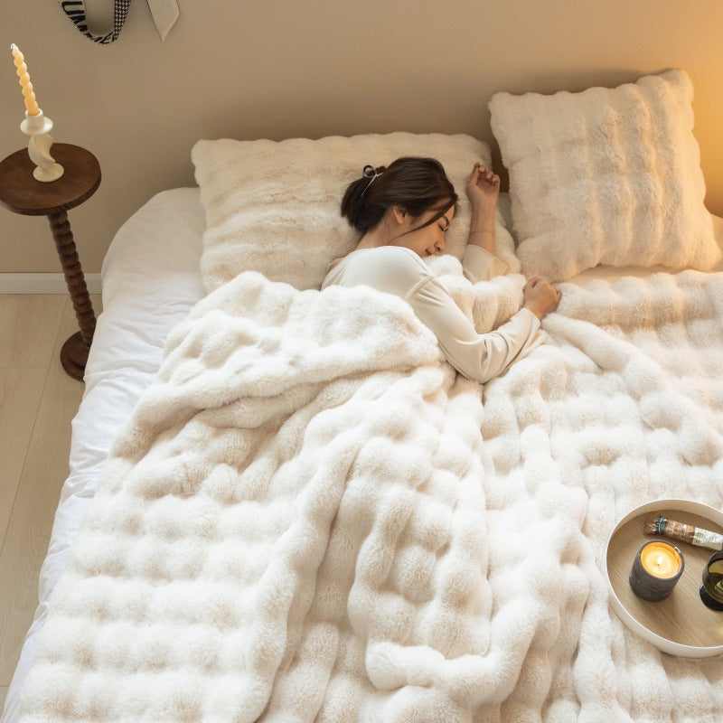 Woman lying in bed under a fluffy white comforter with candles and a tray on the nightstand.